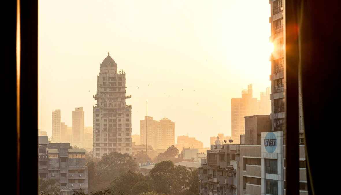 Sonnenaufgang über der Skyline von Mumbai, mit hohen Gebäuden im goldenen Licht.