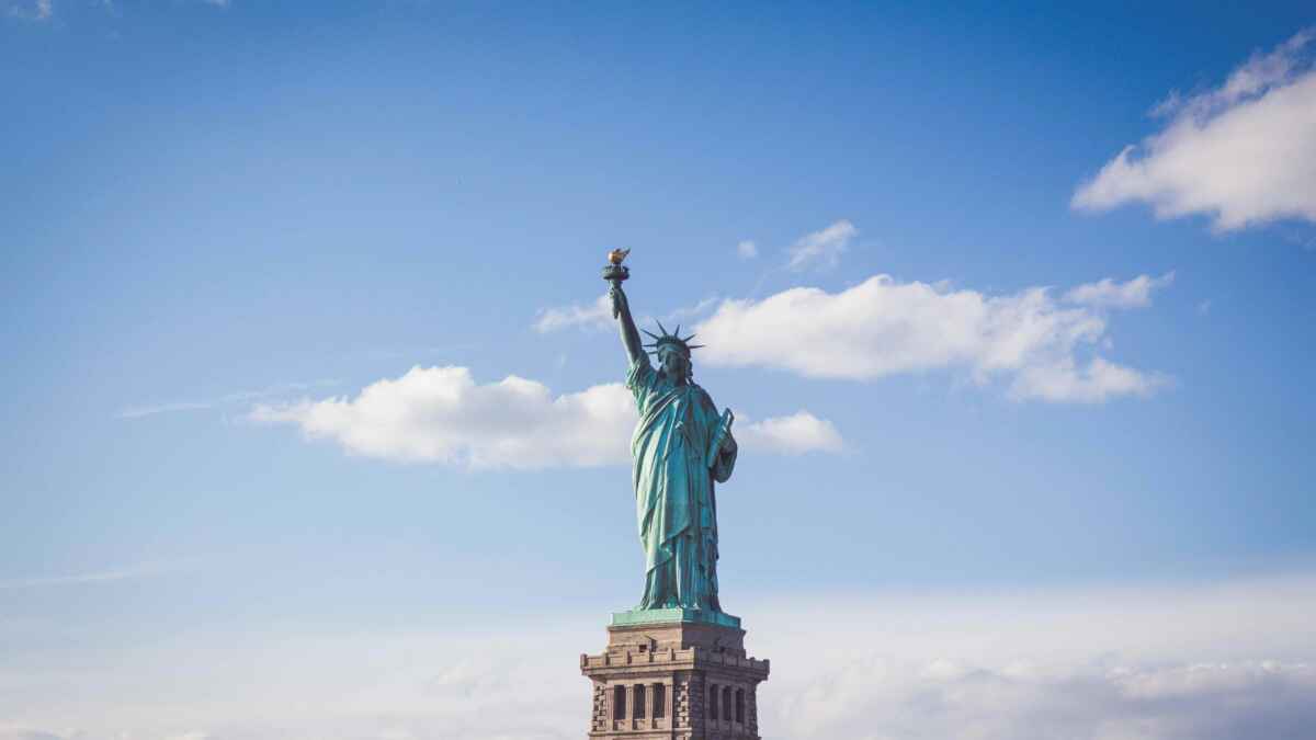 Freiheitsstatue in New York City vor blauem Himmel mit einigen Wolken. Majestätische Darstellung der ikonischen Statue.
