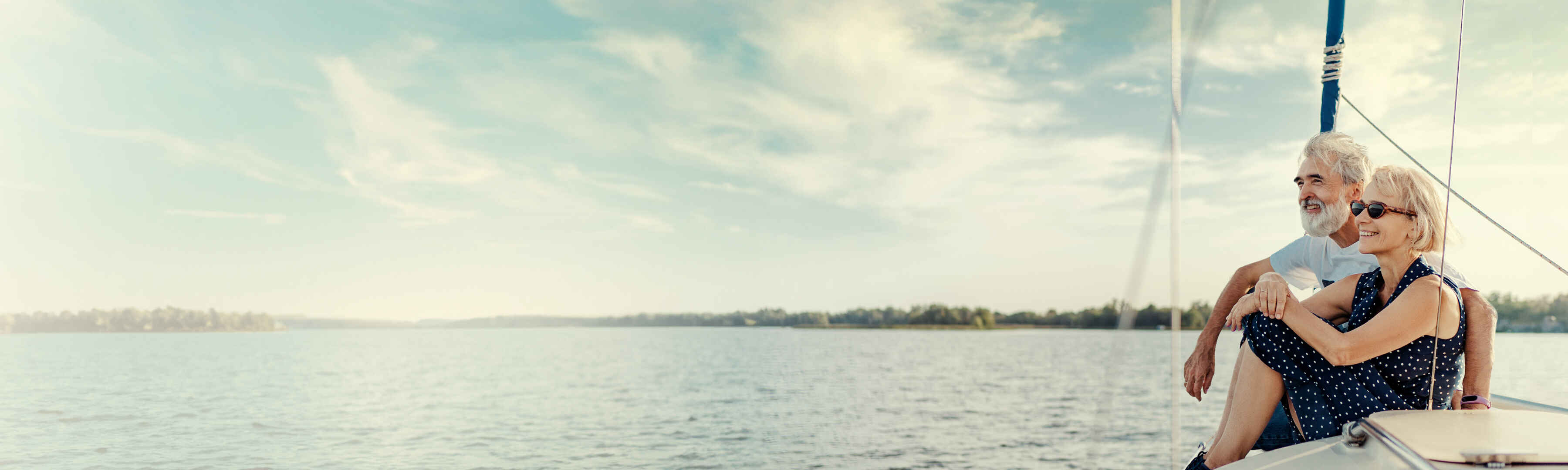 Älteres Paar genießt entspannt die Aussicht auf einem Segelboot bei sonnigem Wetter auf dem offenen Wasser.