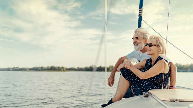Älteres Paar genießt entspannt die Aussicht auf einem Segelboot bei sonnigem Wetter auf dem offenen Wasser.