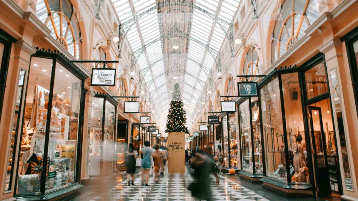 Elegante Einkaufspassage mit gläsernem Dach, Weihnachtsbaum in der Mitte, Menschen beim Bummeln in Melbourne Arcade.