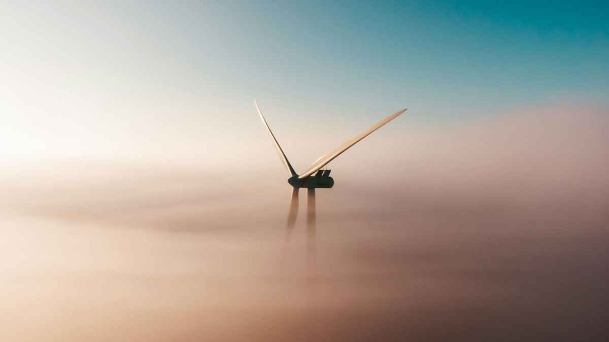 Windturbine in Nebellandschaft unter blauem Himmel zur Energiegewinnung.